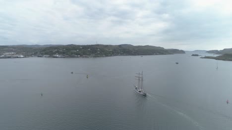 Aerial-shot-of-a-tall-ship-arriving-in-to-Oban-bay,-Scotland,-on-a-cloudy-day