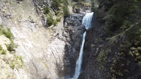drone-view-of-a-cascade-in-between-rocks-in-the-swiss-alps