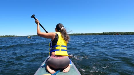 Girl-doing-paddleboarding-while-sitting-on-her-knees
