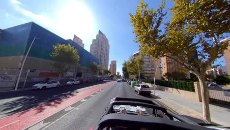 An-open-roof-car-speeding-on-empty-road-with-a-halt-at-the-traffic-signal-during-a-bright-sunny-day-in-city