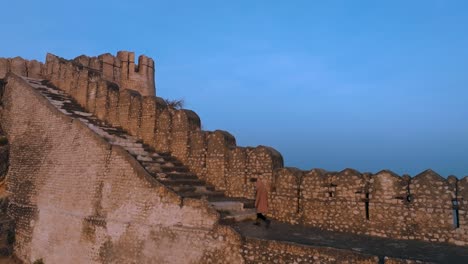 Drone-flight-at-ranikot-fort-in-sindh-pakistan---Man-walking-on-historical-ruin-wall