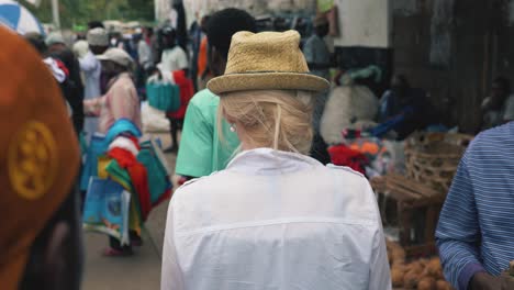 Close-up-shot-of-a-young-girl-walking-on-busy-crowded-street,-traveller-in-noisy-african-market-place