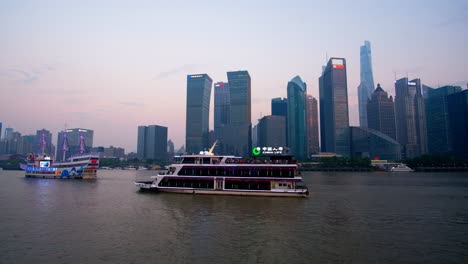 Los-Barcos-Turísticos-Llevan-A-Los-Visitantes-En-Un-Recorrido-Nocturno-Por-El-Famoso-Río-Huangpu-De-Shanghai,-Mostrando-Luces-Espectaculares-En-Los-Edificios-Comerciales-Cercanos.