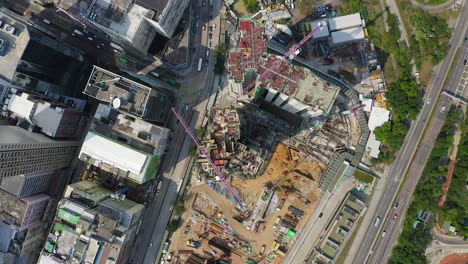 Mega-Building-Construction-site-in-downtown-Hong-Kong,-Pull-up-tilt-down-aerial-view