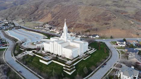 Drone-circles-around-beautiful-building,-LDS-temple-at-the-foot-of-the-mountains