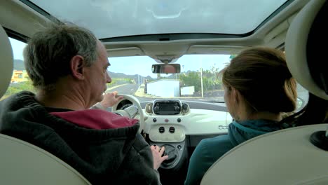Rear-seat-POV-shot-of-old-man-and-daughter-driving-around-town