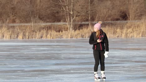 A-young-blonde-girl-is-watching-something-on-her-phone-as-she-skates-in-and-out-of-the-frame