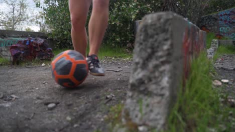 Cierre-De-Una-Chica-Regateando-Una-Pelota-De-Fútbol-Alrededor-De-Las-Rocas,-Controlando-La-Pelota,-Siguiendo-En-Cámara-Lenta