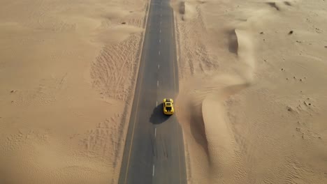 Aufschlussreiche-Drohnenaufnahme-Eines-Chevrolet-Camaro-Inmitten-Verlassener,-Mit-Sand-Bedeckter-Wüstenstraßen-In-Dubai,-Vereinigte-Arabische-Emirate