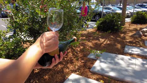 Sabering-Champagne-wine-bottle-using-a-wine-glass-transparent-on-a-beautiful-sunny-day-under-a-tree-shade