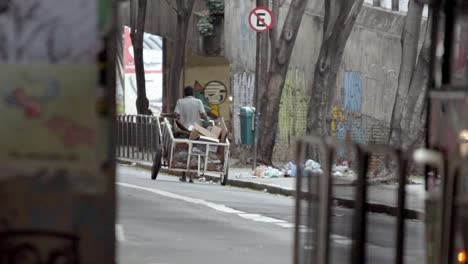 Man-pulling-cart-with-cardboard,-waste-picker