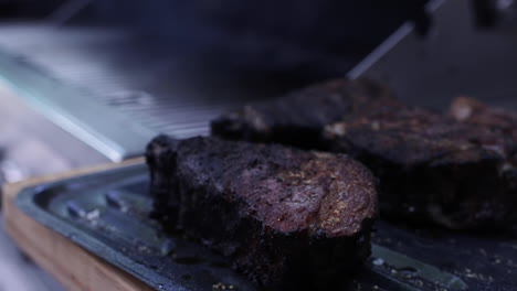 Thick-juicy-charcoal-steak-smoking-on-outdoor-grill,-close-up-shallow-depth-of-field