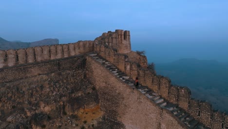 Drohnenflug-über-Der-Ranikot-Festung-In-Sindh,-Pakistan---Mann-Läuft-Auf-Historischer-Ruinenmauer