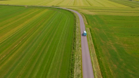 Tilt-down-aerial-view-of-VW-van-driving-through-countryside