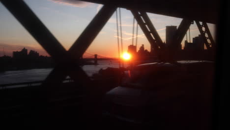 Stunning-slow-motion-shot-of-train-ride-during-sunset-across-the-Williamsburg-bridge,-connecting-Brooklyn-and-Manhattan-in-New-York-City