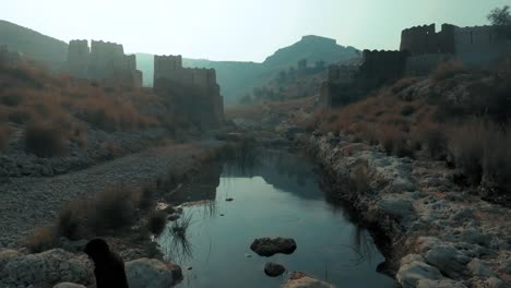 Vuelo-De-Drones-En-El-Fuerte-Ranikot-En-Sindh,-Pakistán,-Sobre-El-Río-Cerca-De-Ruinas-Históricas