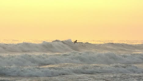 Surfer-Versucht-Ein-Luftmanöver-Zur-Goldenen-Stunde-Mit-Einer-Insel-Im-Hintergrund