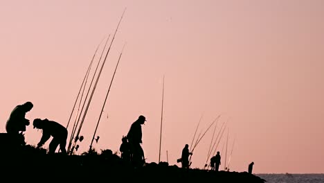 Group-of-fishermen-standing-on-the-bay,-preparing-their-fishing-rods