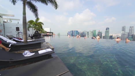 Infinity-Pool-Mit-Blick-Auf-Die-Skyline-Von-Singapur-Mit-Schwimmern-Und-Einem-Rettungsschwimmer,-Der-Weggeht