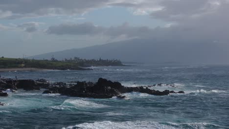 Aerial-telephoto-orbit-around-rocky-shoreline-on-edge-of-Hookipa-Maui