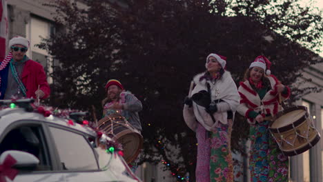 Cámara-Lenta:-Cuatro-Personas-Vestidas-De-Navidad-Caminando-Sobre-Zancos-Y-Tocando-Instrumentos