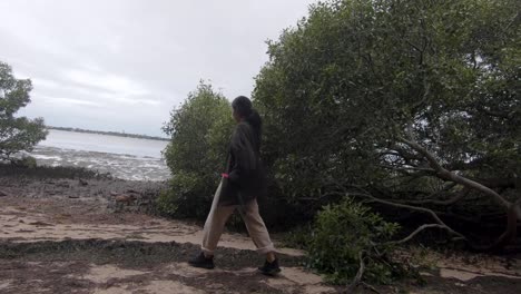 Female-walking-into-an-opening-in-the-forest-during-a-cloudy-day