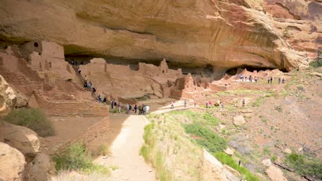 Tourists-climbing-ladders-at-the-Long-House-cliff-dwelling-in-Mesa-Verde-National-Park,-pan