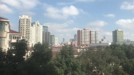 Sunny-daylight-on-a-three-story-townhouse-in-South-Shanxi-Road-with-modern-high-rise-buildings-in-the-background-as-a-typical-mix-of-the-two-worlds-in-Shanghai