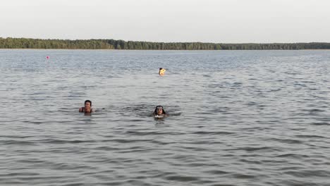 Gente-Nadando-En-Un-Lago-En-Un-Día-De-Verano-Con-Bosque-En-Segundo-Plano.