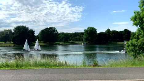 Two-sailboats-a-motorboat-and-a-pedal-boat-drive-over-the-Aasee-lake-at-sunshine-in-Münster-Germany