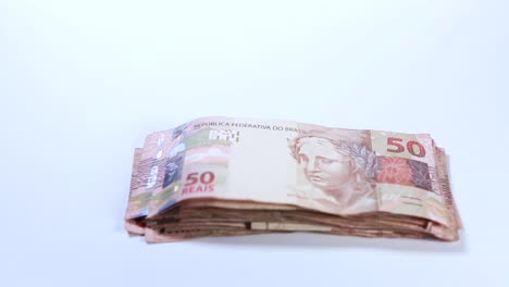 Ein-Stapel-Brasilianischer-Real-Banknoten-Wird-Vom-Wind-Weggeblasen,-Einige-Davon-Bleiben-Oben-Im-Rahmen-Hängen