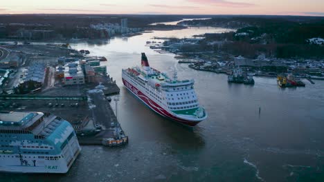 Aerial-view-of-Viking-Line-cruise-ship-Amorella-moving-backwards-when-arriving-to-port-during-lowlight-morning-sunrise
