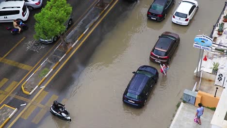 Flooded-street-and-vehicles-passing-through-the-sewage-after-a-massive-storm-in-Kusadasi,-Turkey