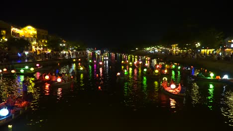 Schwenkaufnahme-Von-Bunten-Booten-Auf-Dem-Fluss-Der-Antiken-Stadt-Hoi-An-Bei-Nacht---Vietnam