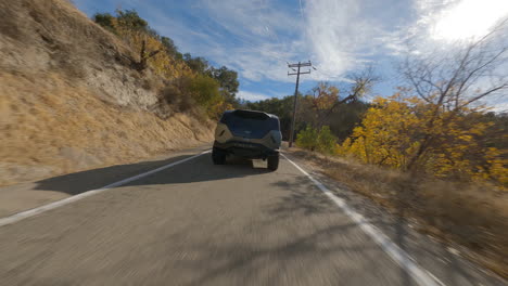 Rotación-Fpv-Y-Siguiente-Toma-De-Rezvani-Conduciendo-Por-Una-Carretera-Pavimentada-En-California