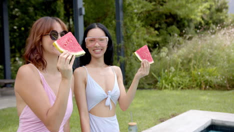 Two-female-friends-are-enjoying-slices-of-watermelon-outdoors-in-the-backyard