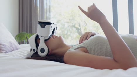 Caucasian-teen-girl-with-brown-hair-explores-VR-at-home-on-a-white-bed