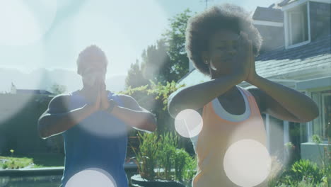 Animation-of-light-spots-over-african-american-couple-doing-yoga,-meditating,-slow-motion
