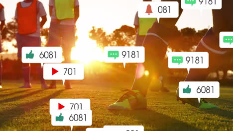 Animation-of-social-media-notifications-over-diverse-male-football-team-training-on-pitch-at-sunset