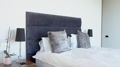 A-modern-bedroom-features-a-large-grey-headboard-and-matching-lamps-with-copy-space