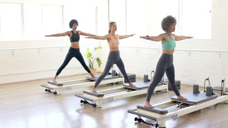 Tres-Mujeres-Practican-Yoga-En-Reformadores-De-Pilates-En-Un-Estudio-Luminoso