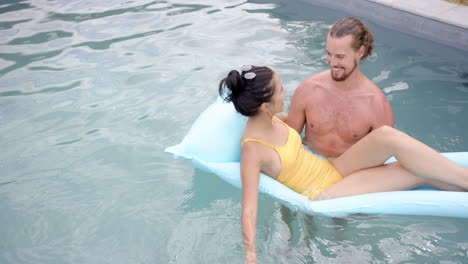 A-young-biracial-couple-enjoys-time-in-a-pool,-copy-space