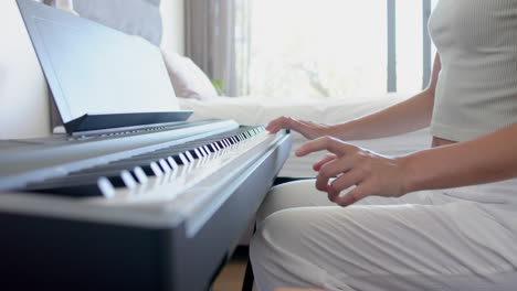 A-teenage-caucasian-girl-is-playing-a-digital-piano,-learning-a-piece