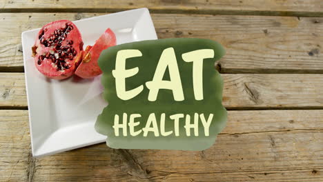 Animation-of-eat-healthy-text-over-pomegranate-on-plate-on-table