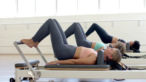 Drei-Frauen-Trainieren-An-Pilates-Reformer-Maschinen-In-Einem-Hellen-Studio