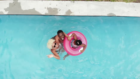 An-African-American-family-floats-on-a-pink-inflatable-ring-in-a-pool-at-home