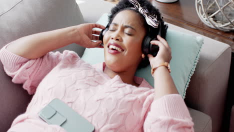 African-American-woman-enjoys-music-on-a-couch-at-home