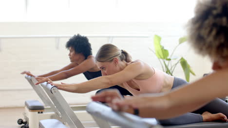 Diverse-group-of-friends-practicing-pilates-in-bright-studio