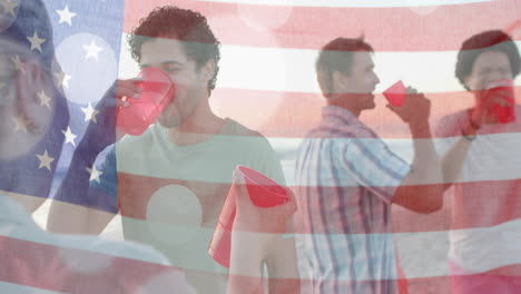 Animation-of-flag-of-usa-over-happy-diverse-friends-at-beach-party-in-summer