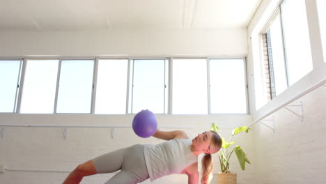 Caucasian-woman-holding-purple-ball-doing-yoga